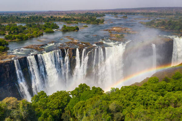 Aerial few of the world famous Victoria Falls with a large rainbow over the falls. This is right at the border between Zambia and Zimbabwe in Southern Africa. The mighty Victoria Falls at Zambezi river are one of the most visited touristic places in Africa.